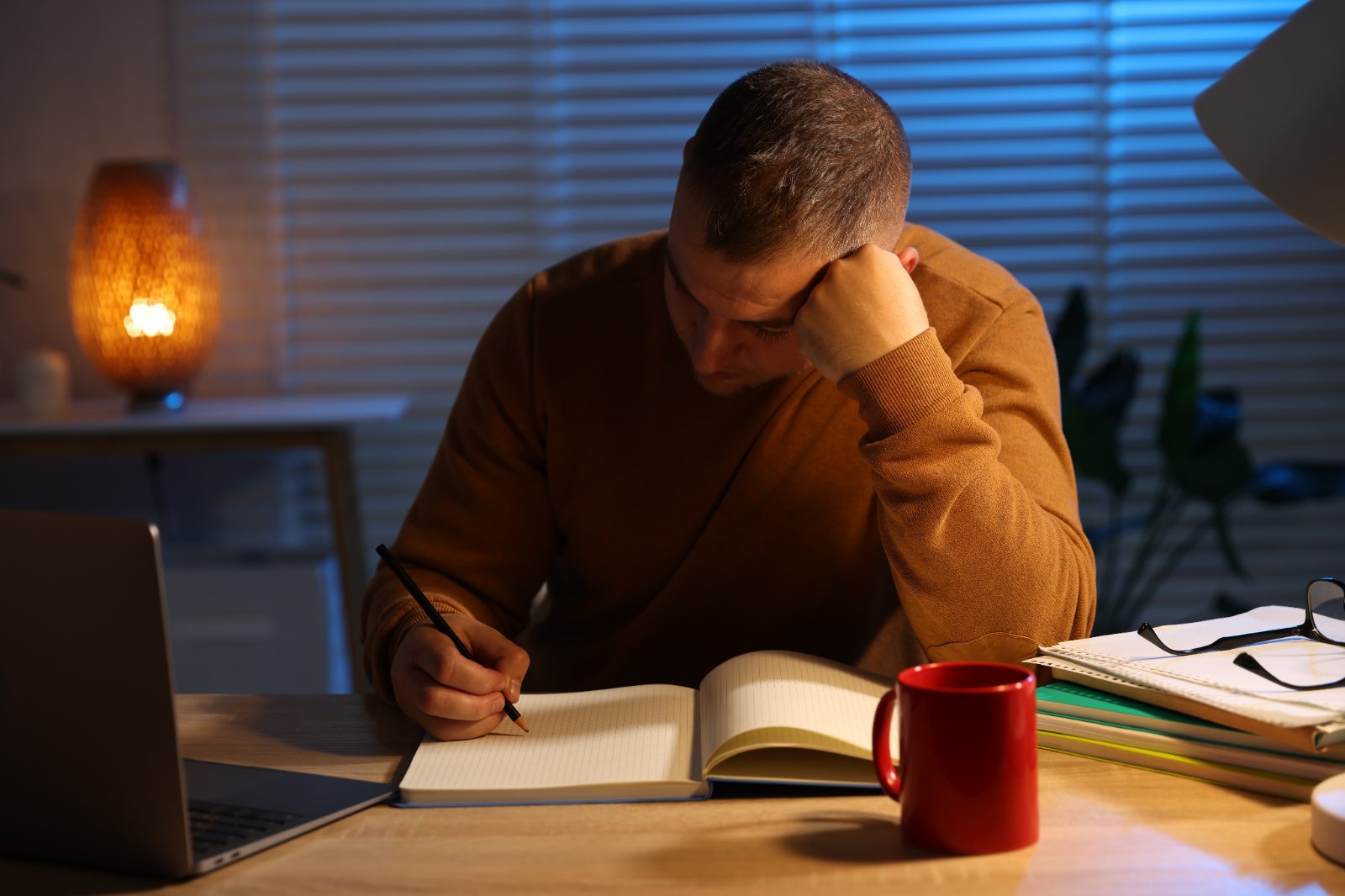 Adult student studying safely at home at night, warm lamplight