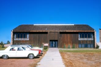 The Classroom Building (Leist Hall) and unpaved parking lot.